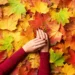 women hands with brown nail polish above fall colored leaves
