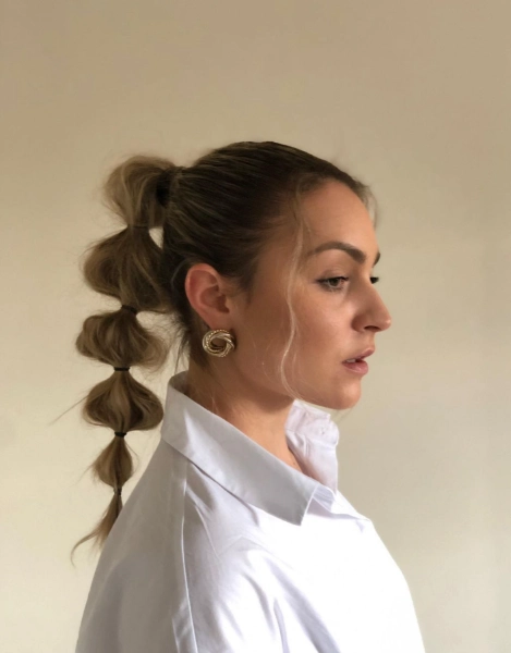 a young woman with dark blonde a high bubble ponytail