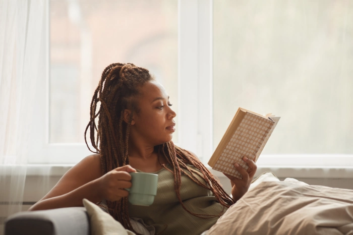 a woman is laying on the couch and reading a book