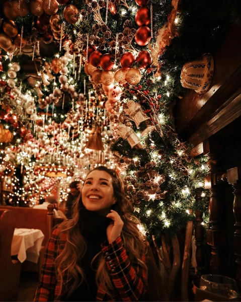 a young woman sitting in a holiday pop-up bar with sparkling lights