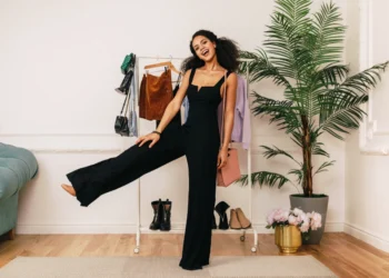 a young woman with black curled hair wearing a black jumpsuit as her cute birthday outfit