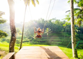 a woman swings near a forest in bali