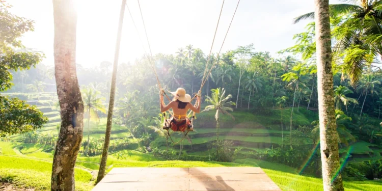 a woman swings near a forest in bali