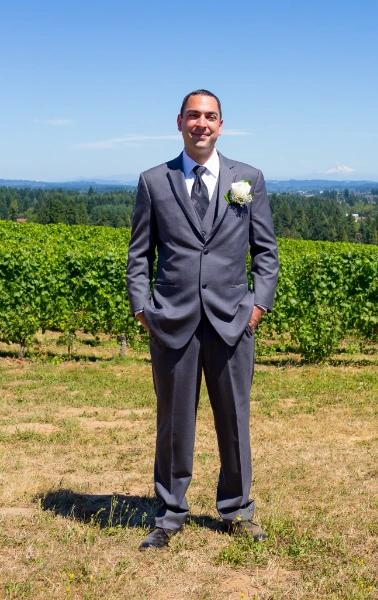 a man in a fall wedding attire standing on a hill