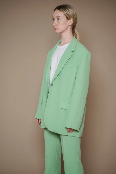 a young blonde woman wearing a white shirt an a light green pastel suit