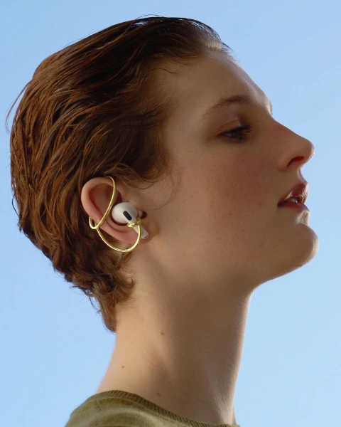 a young red and short haired woman wearing earbuds with jewelry