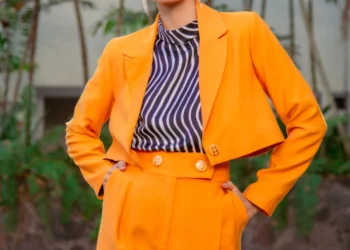 a woman in an orange suit with a blue-white lined blouse