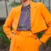 a woman in an orange suit with a blue-white lined blouse