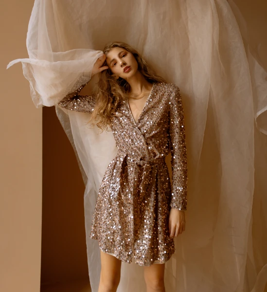 a young blone woman wears a beige sequin dress