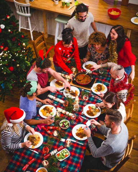 family and freinds sitting on a table and celebrating the christmas spirit