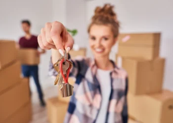 a young couple moving in an apartment. boxex in the background. the woman halding the keys in her hands