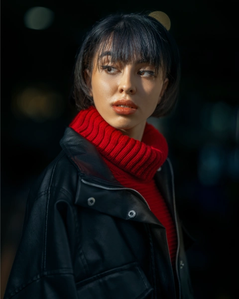 a black haired woman with a leather jacket and a red turtleneck shirt