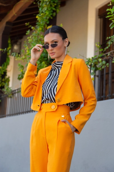 a young black haired woman in an orange pant suit
