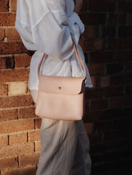 a woman with a beige top handle bag