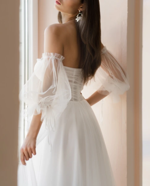 a young brunette woman in a sleeve wedding dress
